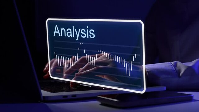 Focused work on data analysis in a dark room with glowing screen showing information and graphs on a laptop.