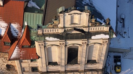Close-up aerial shot of an ornate stone cross on a church roof with snow.  © Adrian