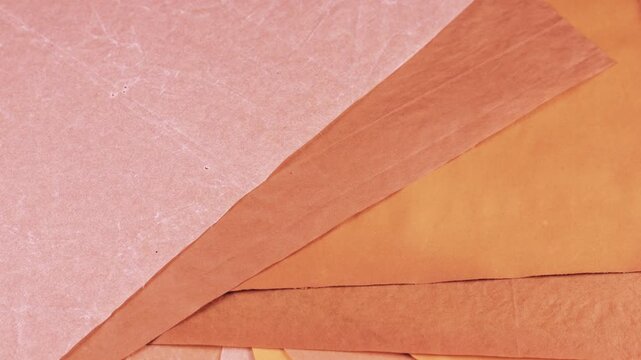 Textured sheets of handmade paper in earthy pink, sakura and terracotta tones rotate slowly to reveal a natural grain. This eco-friendly craft material features a vintage grunge surface.