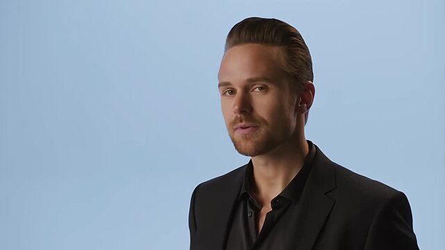 Man in black suit looking at camera with a slight smirk, corporate portrait man male suit black suit.