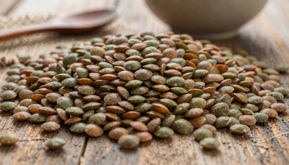 Obraz premium Pile of Raw Brown and Green Lentils on Rustic Wooden Surface with Spoon and Bowl in Background - Healthy Food Ingredient