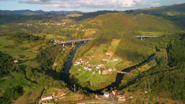 Epic bridge river meander reveal. 
Cinematic drone tilt down 
to modern highway viaduct 
over Nora river valley 
in Asturias, Spain. 
Sustainable infrastructure.
