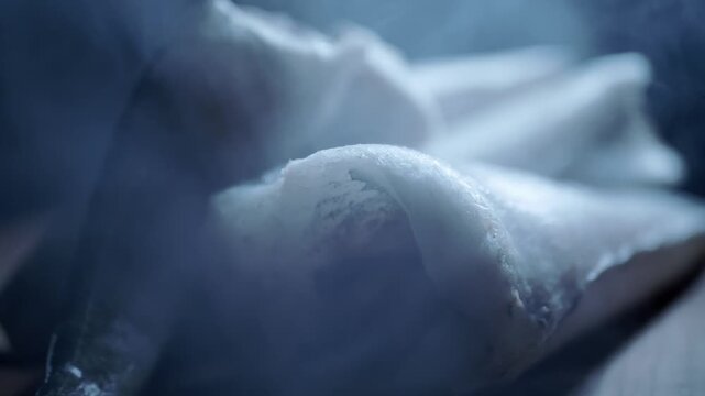 Frozen raw hake fish fillets covered in thick frost sit surrounded by cold billowing vapor. Concept of seafood preservation, deep freezing techniques, and culinary preparation.