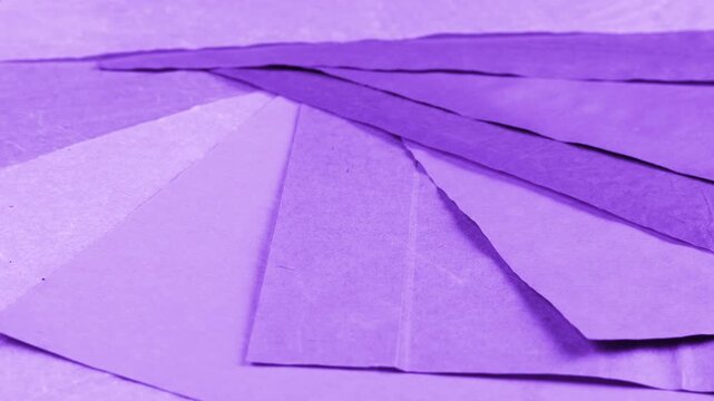 Rotating sheets of handmade paper in various shades of purple, periwinkle and lilac show a rich natural dye texture. This eco-friendly craft background features recycled materials.