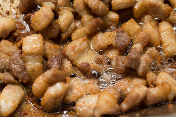 Pork belly slices being rendered in a pan until fully cooked, releasing a large amount of pork fat oil, sizzling golden pork belly during cooking