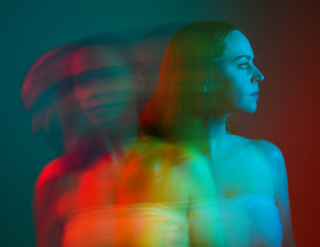 Close up studio portrait of female model face with creative neon studio lighting and slow shutter speed creating colourful blue and red 3d surreal effect.
