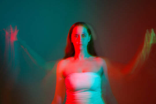 Close up studio portrait of female model face with creative neon studio lighting and slow shutter speed creating colourful blue and red 3d surreal effect.