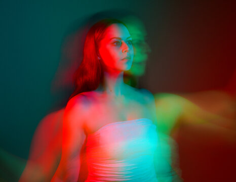Close up studio portrait of female model face with creative neon studio lighting and slow shutter speed creating colourful blue and red 3d surreal effect.