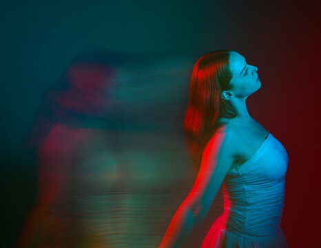 Close up studio portrait of female model face with creative neon studio lighting and slow shutter speed creating colourful blue and red 3d surreal effect.