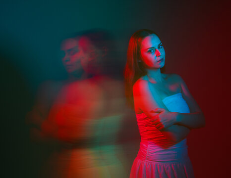 Close up studio portrait of female model face with creative neon studio lighting and slow shutter speed creating colourful blue and red 3d surreal effect.