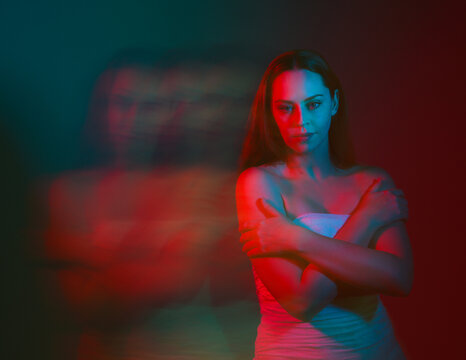 Close up studio portrait of female model face with creative neon studio lighting and slow shutter speed creating colourful blue and red 3d surreal effect.