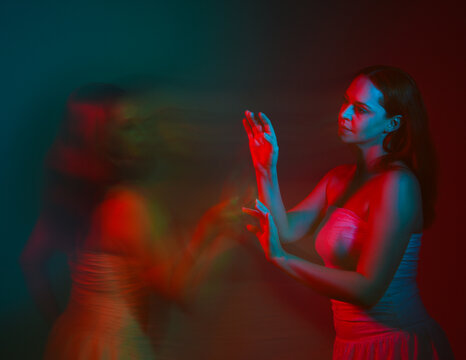 Close up studio portrait of female model face with creative neon studio lighting and slow shutter speed creating colourful blue and red 3d surreal effect.