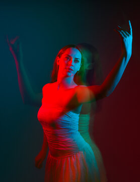 Close up studio portrait of female model face with creative neon studio lighting and slow shutter speed creating colourful blue and red 3d surreal effect.
