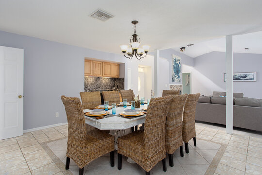 Dining table in blue open living space with formal wicker chairs and tropical table setting