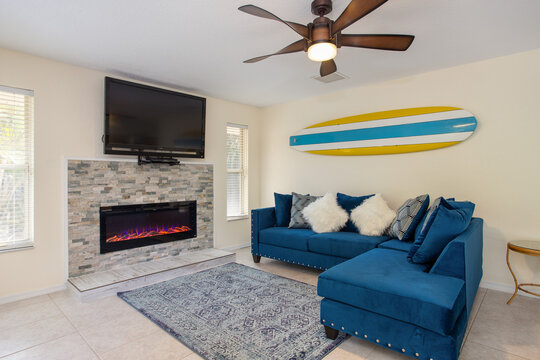 Bright family room in a Florida vacation home with fireplace feature and surf decor