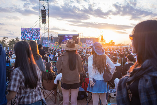 People enjoying outdoor music festival crowd watching live concert at sunset