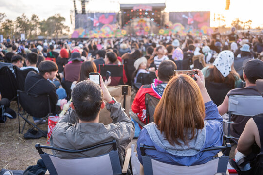 Crowd watching live music concert while recording stage with smartphones