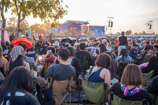 Large outdoor music festival crowd watching live concert at sunset stage
