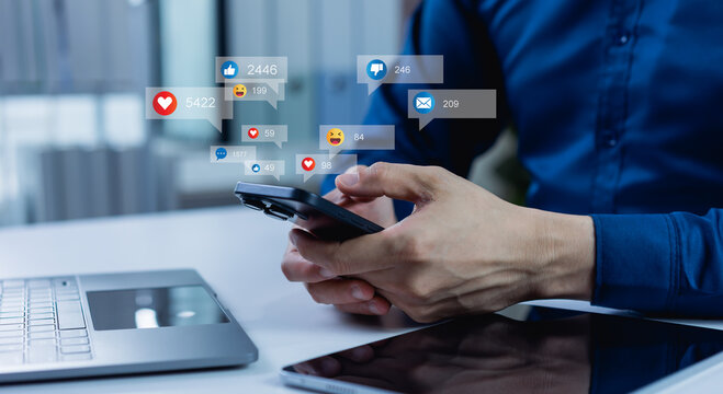 A man uses a smartphone to interact with friends through chat, blog posts, livestream, and emoticon reactions on social media, driving engagement, likes, and digital marketing communication.