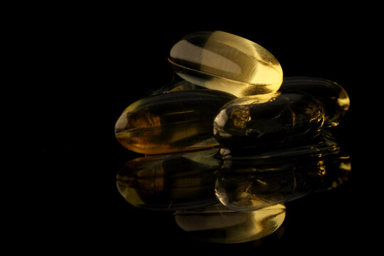 Golden oil capsules reflecting on a dark background