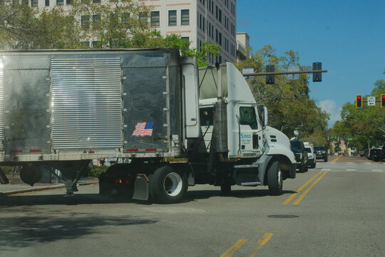 White Sysco Food Semi Truck Making A Turn On City Street With American Flag Trailer Sticker. Editorial Use Only March 6, 2026 St. Petersburg, FL USA. Other cars waiting at the intersection under clear
