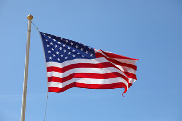 Fototapeta premium The United States flag is flying against a blue sky