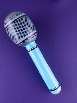 Close-up of a fun  blue inflatable microphone toy for entertainment on a purple background.