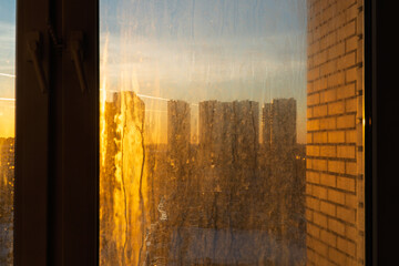 Fototapeta premium Dirty and dusty dark window glass in the sunset. Abstract dirty window glass background. Window with very dirty and dusty glass in daylight in the sunset. Condensation on the fogged windows glass. 