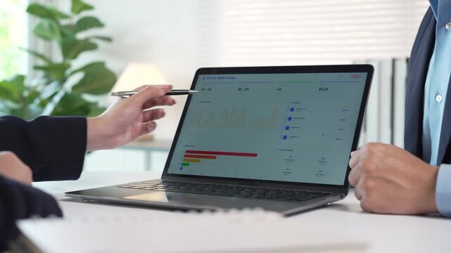 Business people analyzing financial data on a laptop screen during a corporate meeting