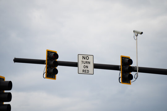 Overhead signal assembly with red traffic lights, surveillance camera and NO TURN ON RED notice, capturing roadway safety, compliance and intersection management