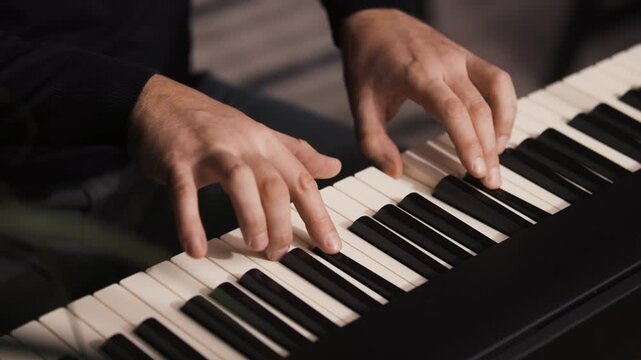 Beginner pianist, male hands practicing on a electronic piano keyboard at home