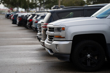 Front quarter view of large parked vehicles along a damp parking row in Florida, useful for themes of automotive market demand, suburban driving and fleet style lineup