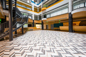 Naklejka premium Modern architectural atrium with geometric patterned floor tiles and spiral staircase