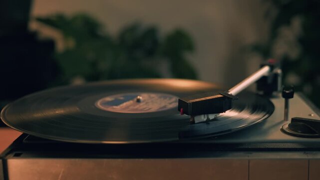 Retro Vinyl record player playing music, close-up macro shot of vintage LP disc old phonograph spinning. Retro music player at home.