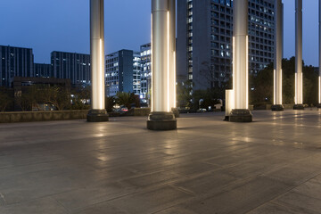 Urban plaza at dusk with illuminated columns and modern high-rise buildings © zhu difeng