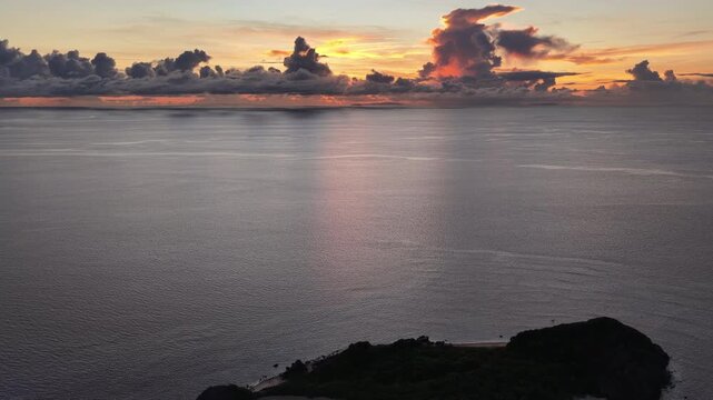 A serene sunrise silhouettes a small island in the Vatu-i-ra seascape in Fiji. This area is a marine protected area known for its high biodiversity and is a destination for divers and snorkelers.