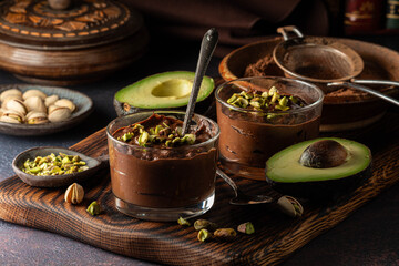 Chocolate avocado mousse in glass dessert dishes, topped with pistachios nuts.