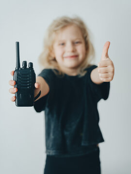 A child girl shows a wireless radio and a thumbs up. Communication with the child and home safety.