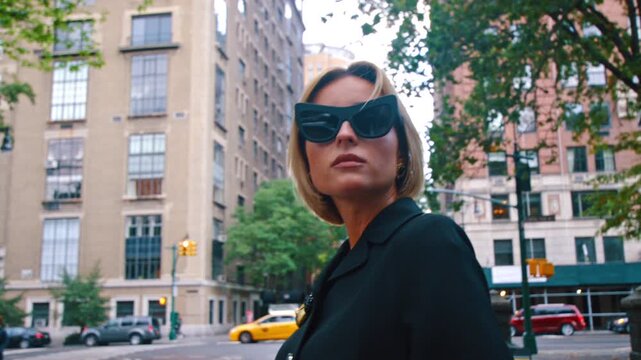 Portrait of a stylish blonde woman in sunglasses and black coat. Modern lady in the bog city.