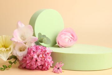 Empty podiums and spring flowers on beige background, closeup. Mockup for design