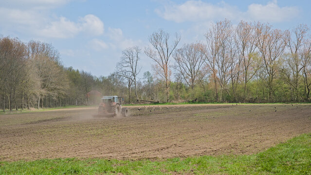  Tractor ploughing farmland on a sunny spring day near Ghent, Flanders, Belgium 