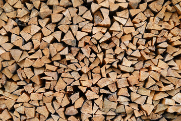 Stacked firewood background. Pile of chopped wooden logs arranged in a stack, natural wood texture and pattern.