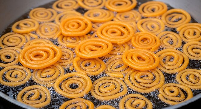 Crispy spiral shaped jalebis frying in hot oil
