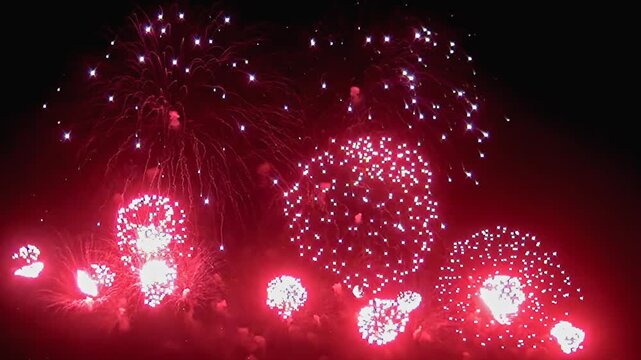 Witness an enchanting spectacle as vibrant fireworks burst in the night sky, illuminating the dark with stunning colors and intricate patterns that captivate the audience.