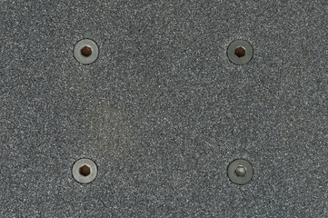 Close view of a skateboard deck with grip tape and screws © PixieMe