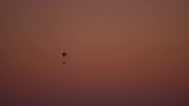 4K Silhouette shot of a paraglider enjoying adventure activity in rann of Kutch desert during the sunset as seen from Kutch in Gujarat, India. Adventure Travel background with copy space.