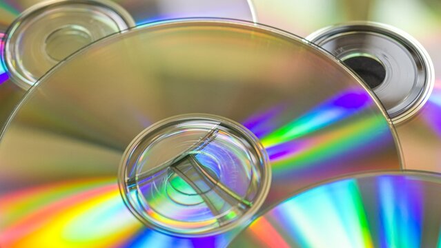 Wide 16:9 close-up of iridescent compact discs with shallow depth of field