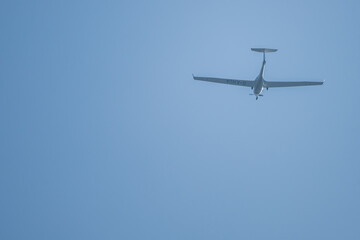 Fototapeta premium Ein Flugzeug fliegt hoch am Himmel über der Stadt während eines sonnigen Tages im Frühling