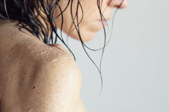 Close-up side view of a naked woman's wet shoulder after a shower