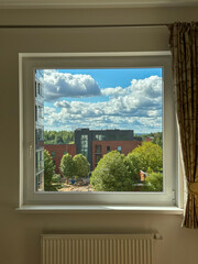 Fototapeta premium View of summer sky and residential buildings through apartment window